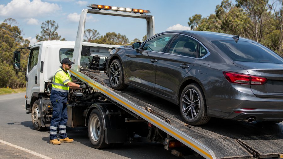 Professional tow truck operator loading a vehicle onto a tilt tray truck in Sydney