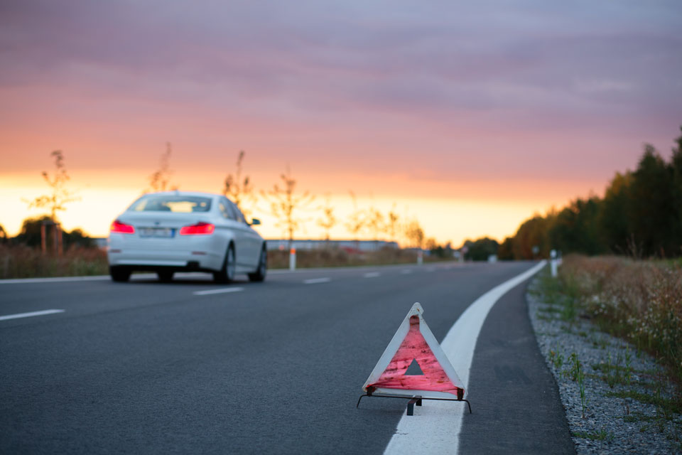 Road safety emergency road triangle at the side of the road at sunset