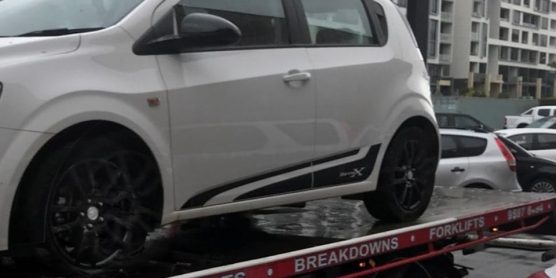 A car with a flat tyre and other things wrong with it on the back of a Fast Sydney Tow Truck.