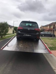 A VW gold GTI getting towed out of Sydney Australia. 