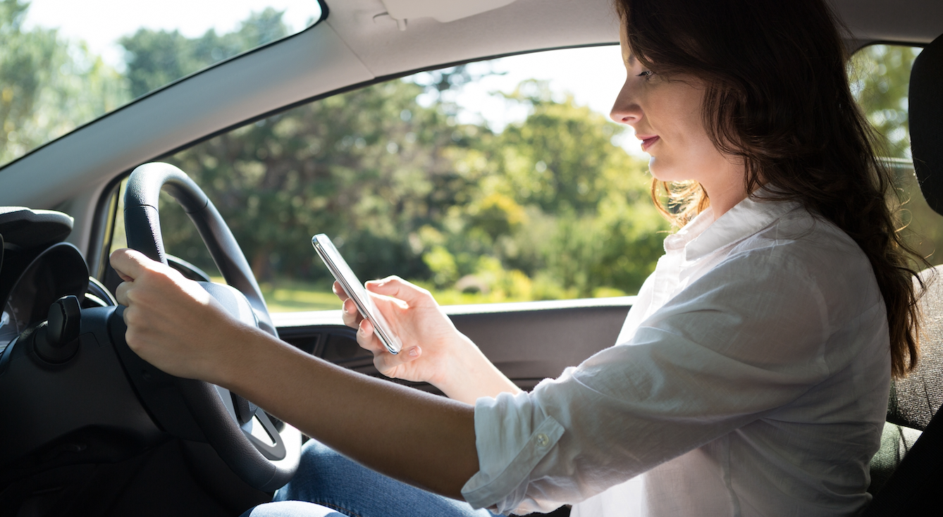 A woman driving while texting.