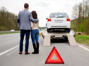 Couple looking at their car being towed. 