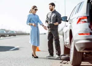 Woman driver with broken down car being assisted.