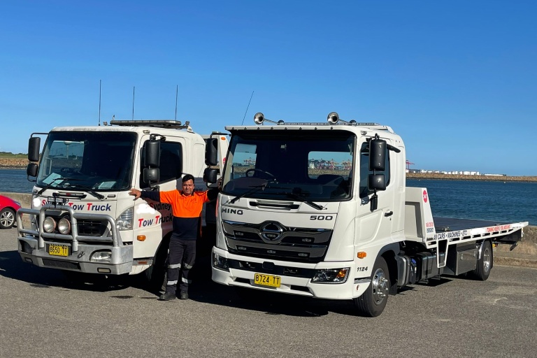 A towing operator standing next to tow trucks in Sydney.