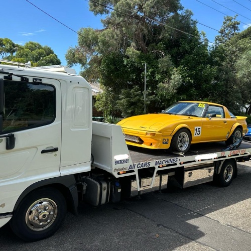 A Fast Sydney Tow truck towing a classic yellow mazda.