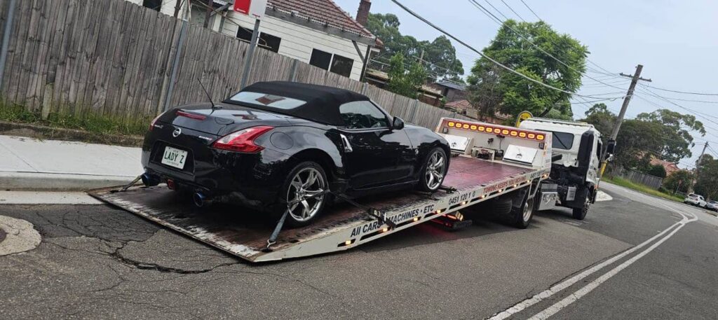 A tilt tray tow truck towing a nissian 370Z.