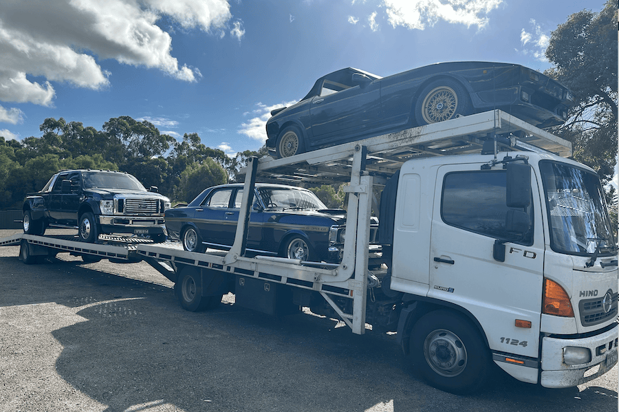 A heavy-duty tilt-tray truck transporting multiple vehicles, illustrating Fast Sydney Towing’s interstate and long-distance towing services.