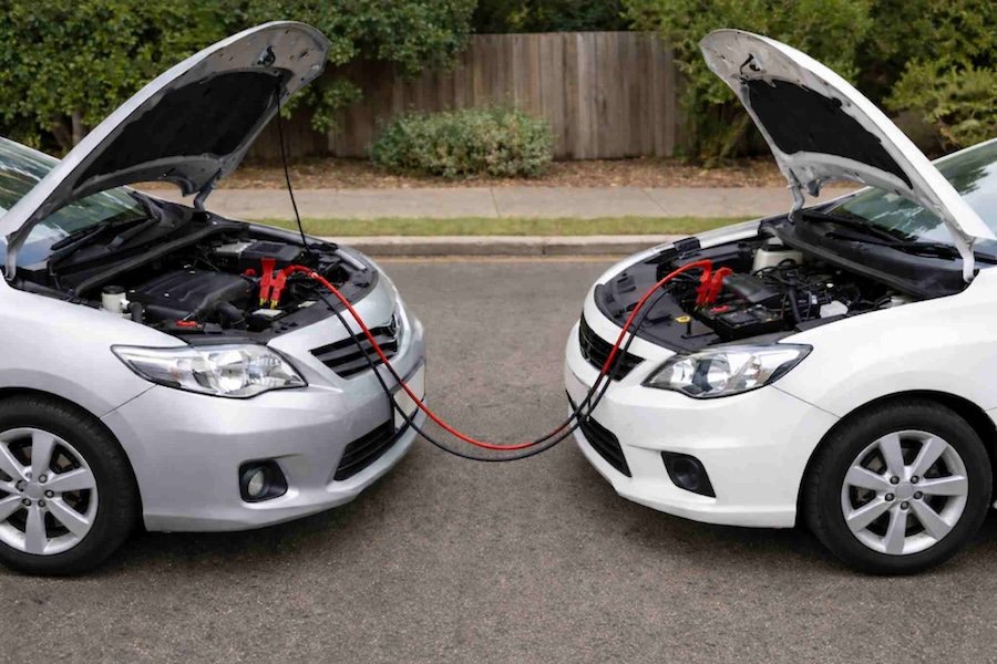 Two cars connected with jumper cables to jump start a car battery safely on a suburban street in Sydney, Australia.