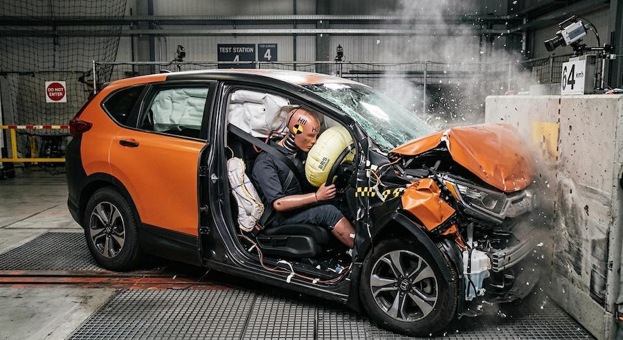 car crash test showing driver dummy restrained by seat belt during frontal impact