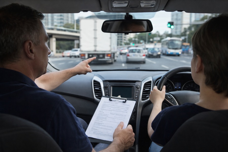 Driving instructor teaching a learner driver hazard awareness in busy Sydney traffic during a driving lesson