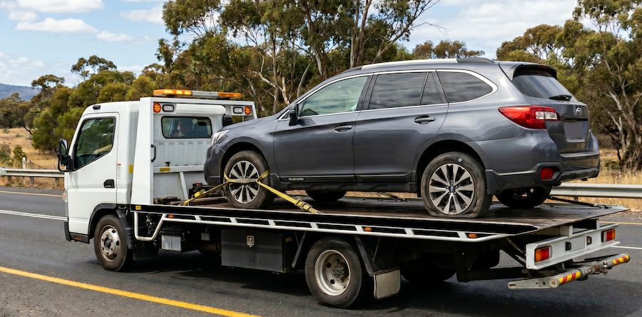 Tow truck transporting a vehicle with a flat tyre on a Sydney road after a roadside breakdown.