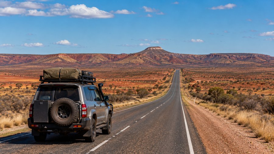 4WD travelling along a remote outback highway in New South Wales surrounded by red desert landscapes
